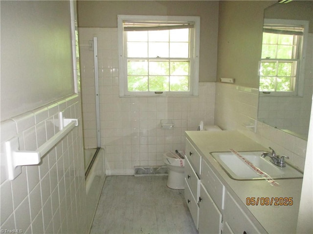 bathroom featuring tile walls, toilet, vanity, bathing tub / shower combination, and wood finished floors
