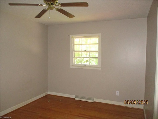 spare room featuring wood finished floors, baseboards, and a ceiling fan