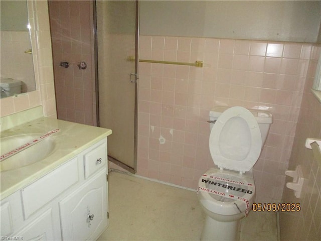 full bath with tile walls, a shower stall, vanity, and toilet