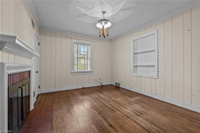 unfurnished living room with built in shelves, an inviting chandelier, and ornamental molding