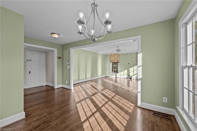 unfurnished dining area featuring ceiling fan with notable chandelier and dark hardwood / wood-style flooring