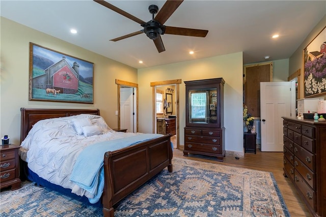 bedroom with ensuite bathroom, hardwood / wood-style flooring, and ceiling fan