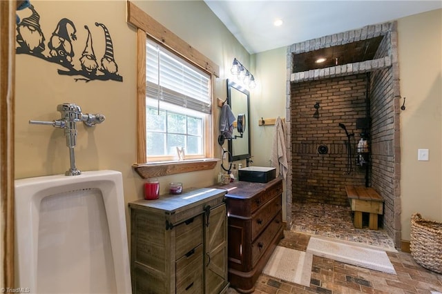 bathroom with tiled shower and vanity