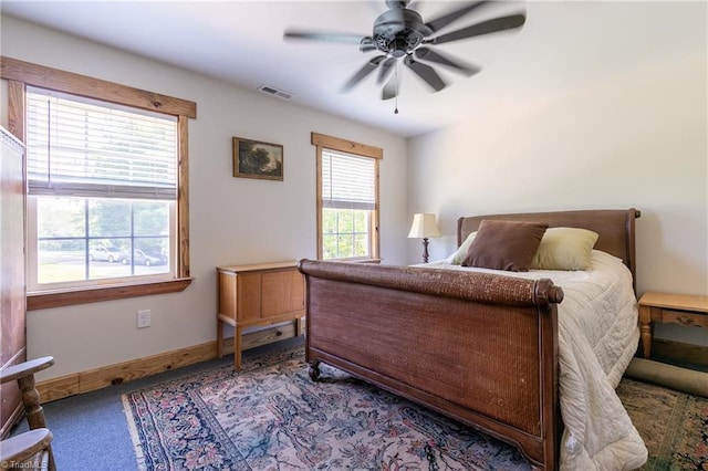 carpeted bedroom featuring multiple windows and ceiling fan