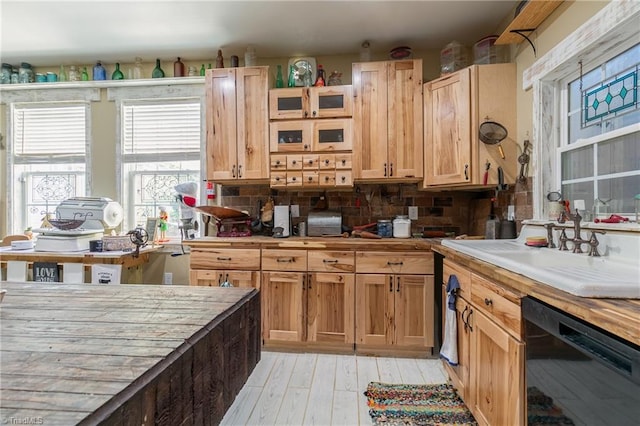 kitchen with decorative backsplash, light wood-type flooring, sink, black dishwasher, and wood counters