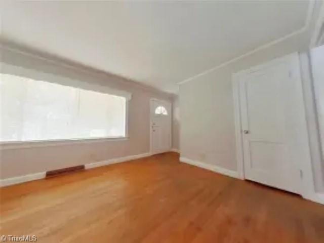 unfurnished room with crown molding, light wood finished floors, and baseboards