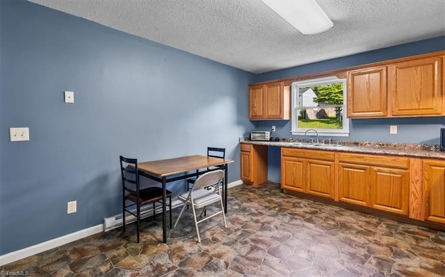 1115 Wachovia St, Winston-Salem, NC 27101 - kitchen featuring a sink, a textured ceiling, dark stone finish flooring, brown cabinetry, and baseboards
