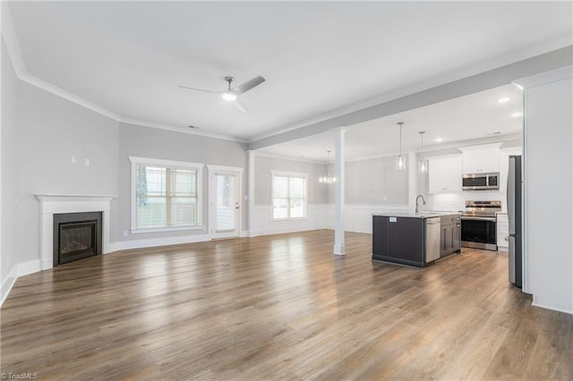 7028 Westfield Village Cir, Summerfield, NC 27358 - unfurnished living room with ornamental molding, a ceiling fan, wood finished floors, a glass covered fireplace, and recessed lighting