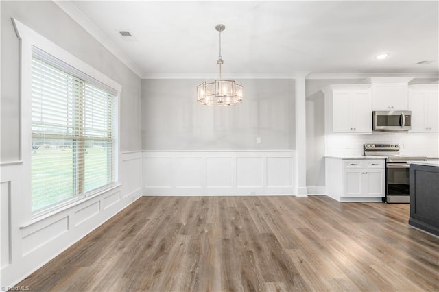 7028 Westfield Village Cir, Summerfield, NC 27358 - unfurnished dining area featuring healthy amount of natural light, a decorative wall, crown molding, a chandelier, and wood finished floors