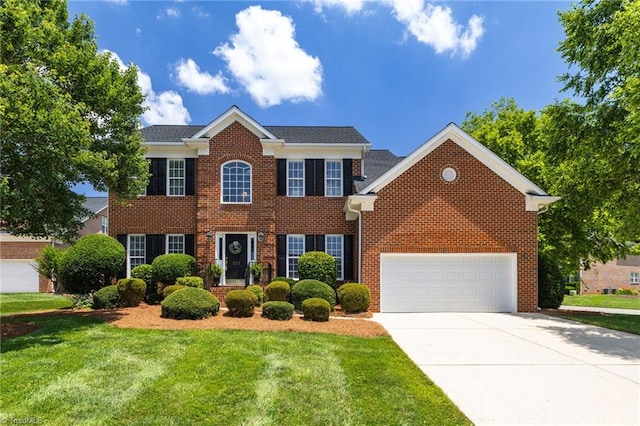 217 Oakmont Park Ct, Kernersville, NC 27284 - colonial house with a front lawn, brick siding, driveway, and an attached garage