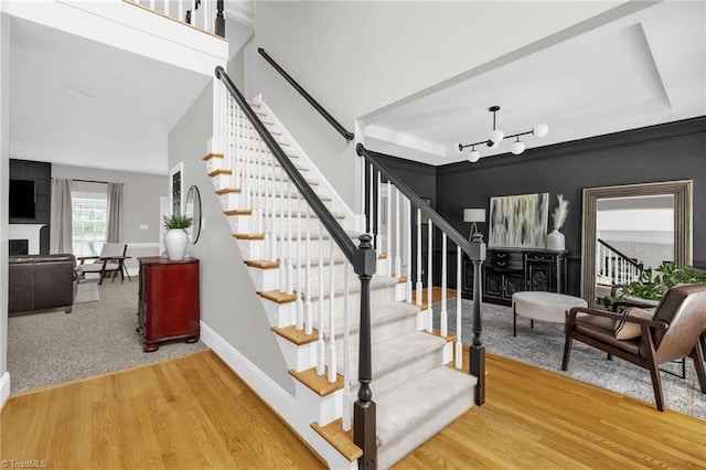 217 Oakmont Park Ct, Kernersville, NC 27284 - staircase with a fireplace, wood finished floors, and a chandelier