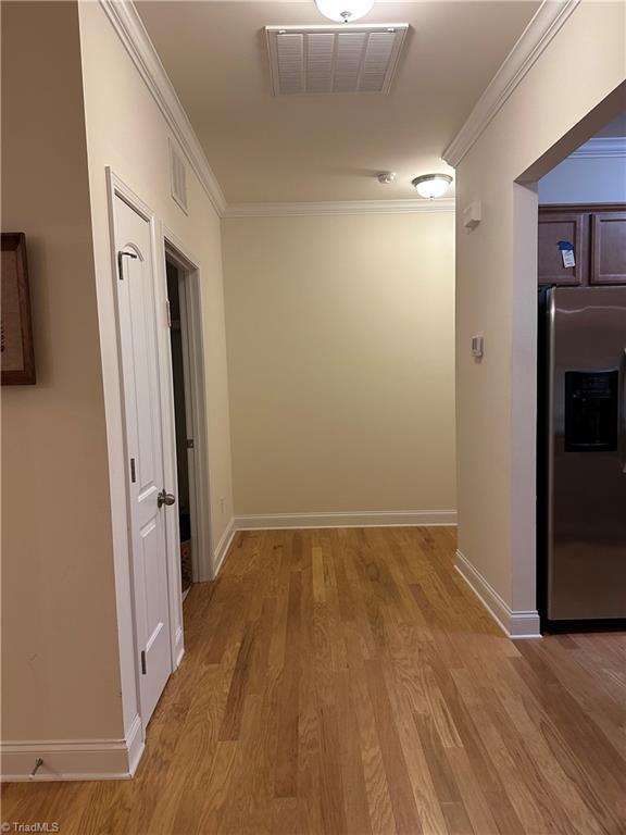 hallway featuring light hardwood / wood-style floors and crown molding