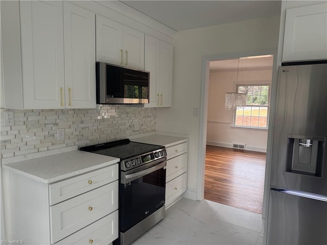 kitchen with tasteful backsplash, white cabinets, and appliances with stainless steel finishes