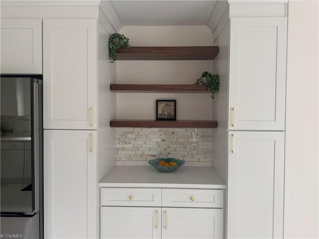 kitchen featuring tasteful backsplash, stainless steel fridge, and white cabinetry