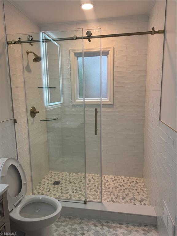 bathroom featuring vanity, toilet, and a shower with shower door