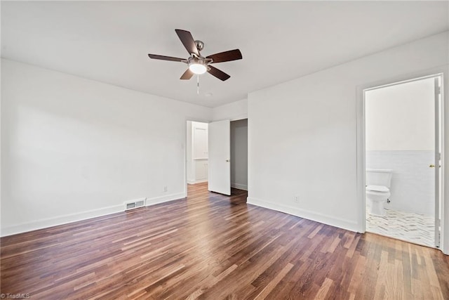 unfurnished bedroom with ceiling fan, ensuite bathroom, and dark hardwood / wood-style floors