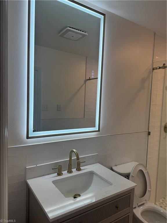 bathroom with vanity, toilet, and tile walls