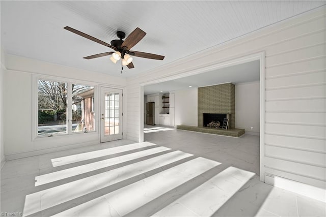 unfurnished living room featuring ceiling fan and a brick fireplace