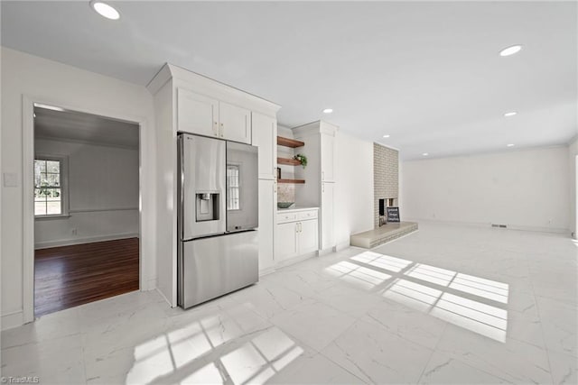 kitchen with white cabinets, stainless steel refrigerator with ice dispenser, and a brick fireplace