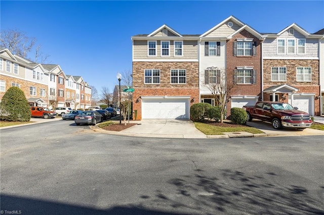 townhome / multi-family property with a garage, a residential view, stone siding, and driveway