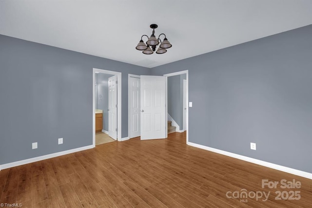 20 Dillingham Pl, Greensboro, NC 27455 - unfurnished bedroom featuring baseboards, a chandelier, wood finished floors, and ensuite bathroom