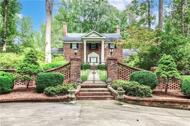 neoclassical home with brick siding and a chimney