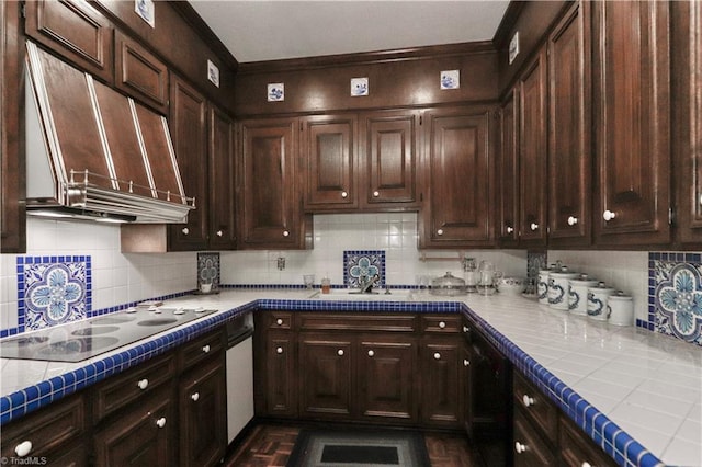 kitchen with black appliances, wall chimney exhaust hood, tile counters, and dark brown cabinetry