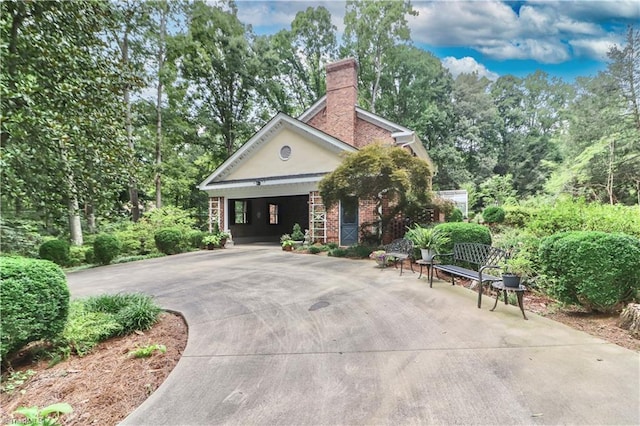 view of front of house with brick siding, driveway, and a chimney