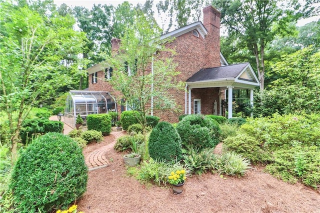 view of front of house featuring an exterior structure, brick siding, an outdoor structure, and a chimney