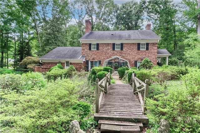 back of property with a chimney and brick siding