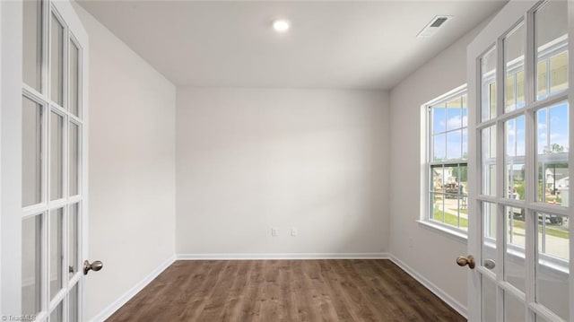 empty room with plenty of natural light, dark hardwood / wood-style flooring, and french doors