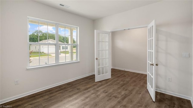 unfurnished bedroom featuring dark wood-type flooring, multiple windows, and french doors