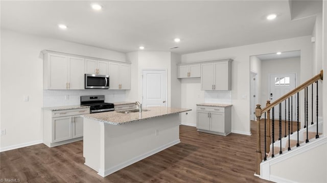 kitchen featuring stainless steel appliances, dark hardwood / wood-style floors, a center island with sink, and sink