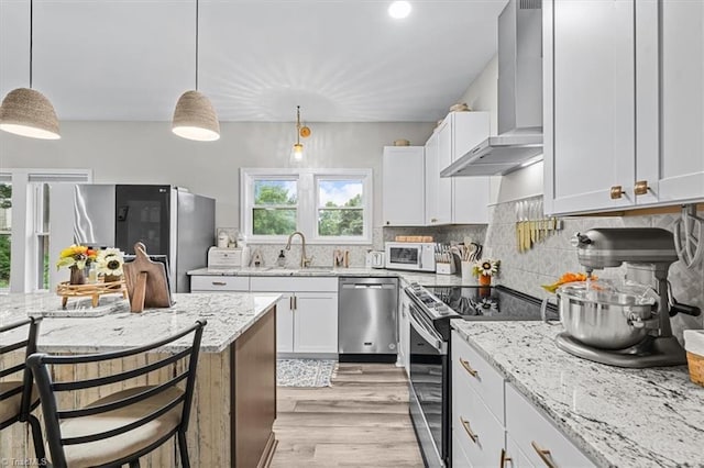 7517 NC Highway 62, Trinity, NC 27370 - kitchen with stainless steel appliances, wall chimney range hood, decorative backsplash, light stone countertops, and light wood-type flooring