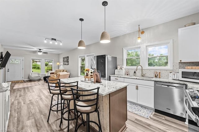 7517 NC Highway 62, Trinity, NC 27370 - kitchen with stainless steel appliances, a kitchen island, light stone countertops, and light wood finished floors