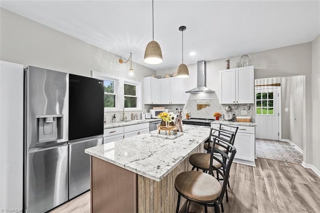 7517 NC Highway 62, Trinity, NC 27370 - kitchen featuring appliances with stainless steel finishes, wall chimney range hood, a kitchen breakfast bar, and light wood finished floors