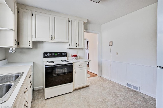 kitchen featuring sink, white cabinetry, and white electric range