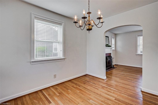 unfurnished dining area with light wood-type flooring and a notable chandelier