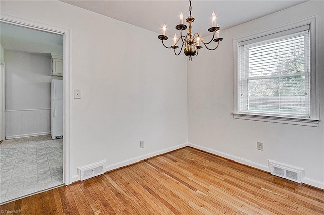 unfurnished room with light hardwood / wood-style floors and a notable chandelier