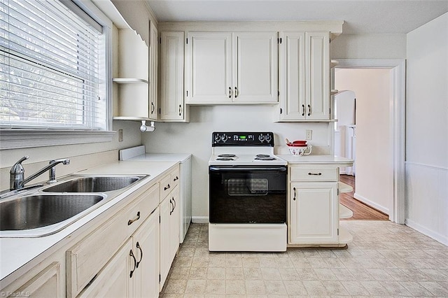 kitchen with white cabinets, sink, and white range with electric cooktop