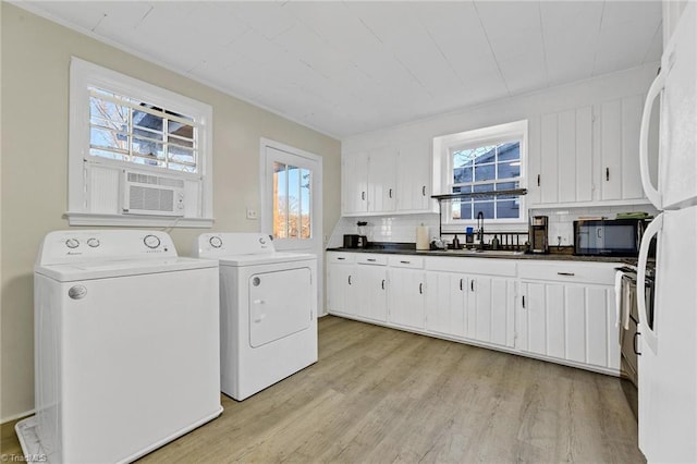 clothes washing area with a wealth of natural light, washer and dryer, light hardwood / wood-style flooring, and sink