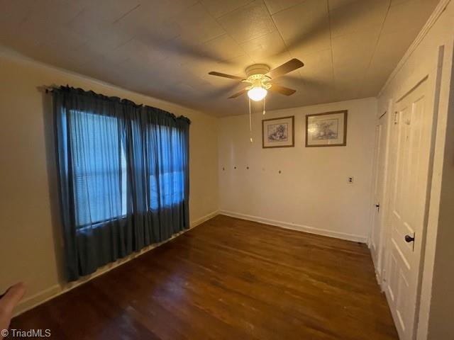 spare room with dark hardwood / wood-style floors and ceiling fan