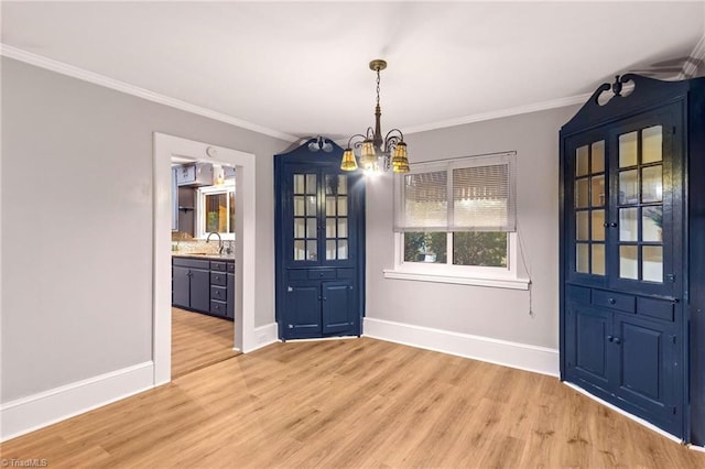 unfurnished dining area with a chandelier, crown molding, sink, and light wood-type flooring