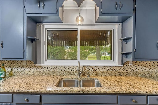 kitchen featuring decorative backsplash, blue cabinetry, and sink