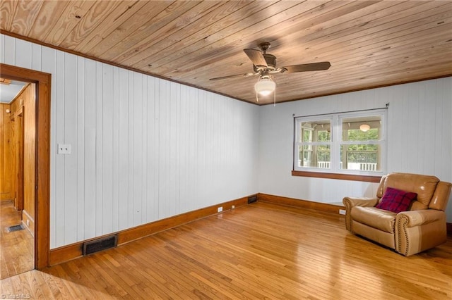 unfurnished room featuring wooden walls, wooden ceiling, light wood-type flooring, and ceiling fan