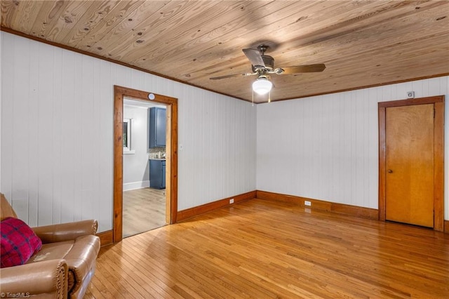 empty room with ceiling fan, wood walls, wood ceiling, and light hardwood / wood-style floors