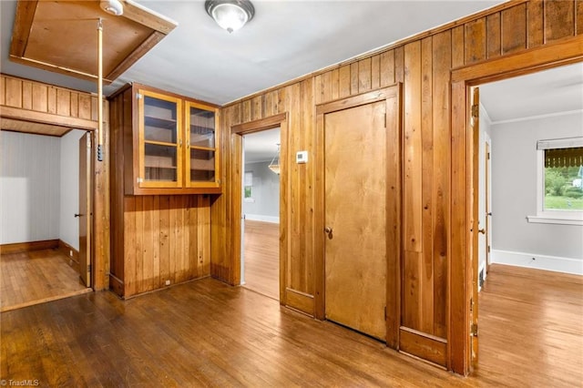 corridor with wooden walls, crown molding, and wood-type flooring