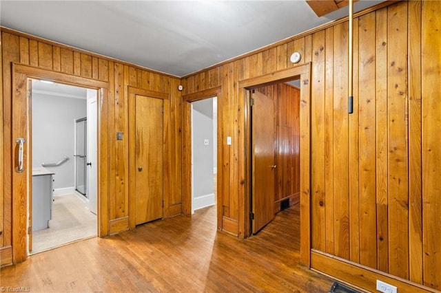 interior space with wood walls, wood-type flooring, and crown molding