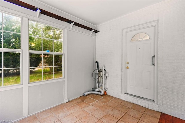 interior space featuring brick wall, light tile patterned floors, and a healthy amount of sunlight