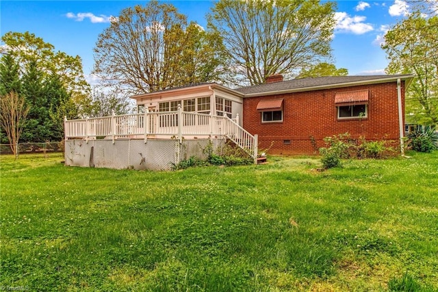 rear view of property featuring a yard, a sunroom, and a deck